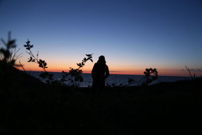 Silhouette woman standing on beach against sky during sunset