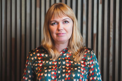 Portrait of young woman standing against corrugated iron
