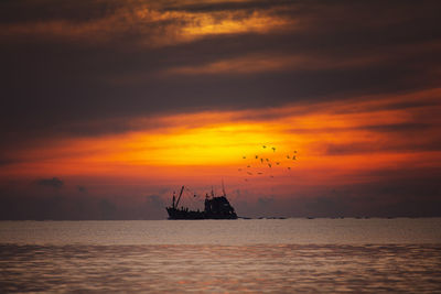 Silhouette boat in sea against sky during sunset