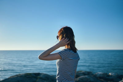 Woman standing in sea against clear sky