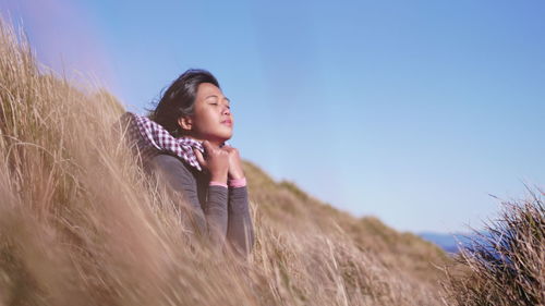 Young woman amidst grass against sky