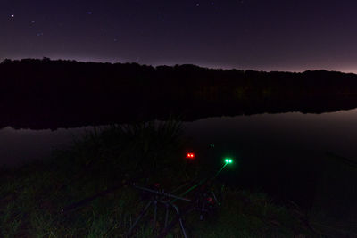 Illuminated light trails on field against sky at night