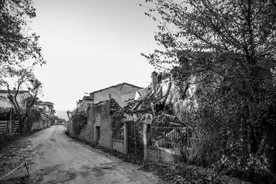 Empty road amidst buildings against clear sky