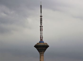 Low angle view of communications tower and building against sky