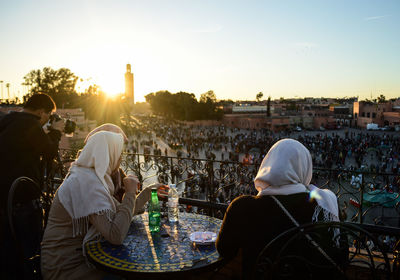 People sitting in city against sky