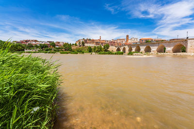 Arch bridge over river against sky in city