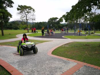 Girl riding beach buggy on footpath at park