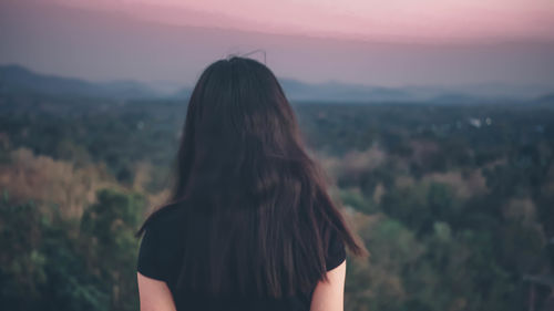 Rear view of woman standing on mountain against sky