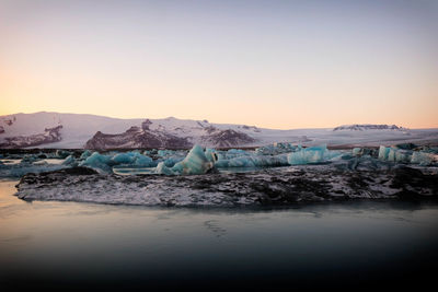 Scenic view of frozen lake against sky during sunset