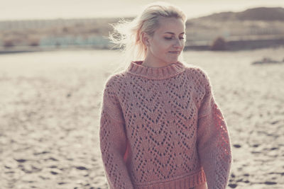 Woman wearing sweater while standing at beach