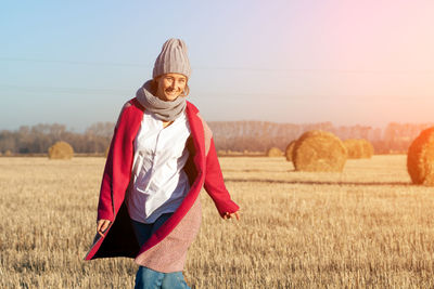 Outdoor close up portrait of young beautiful woman with long hair wearing gray hat, pink coat posing 