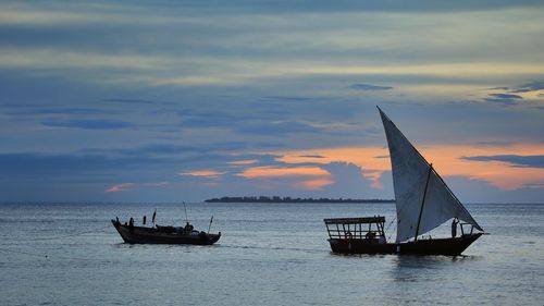 Sailboat sailing on sea against sky during sunset