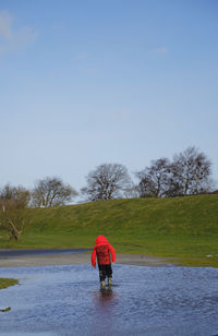 Rear view of woman walking on field against clear sky