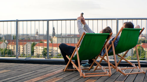 People sitting on table by railing against sky
