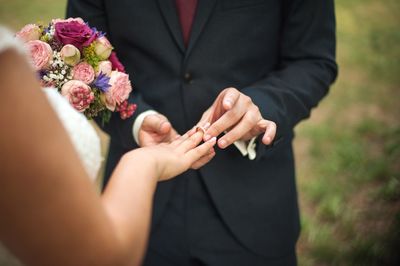 Groom putting wedding ring in finger of bride