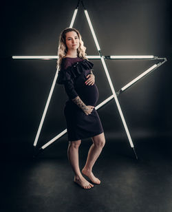 Portrait of young woman standing against wall
