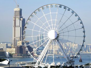 Ferris wheel by lake in city