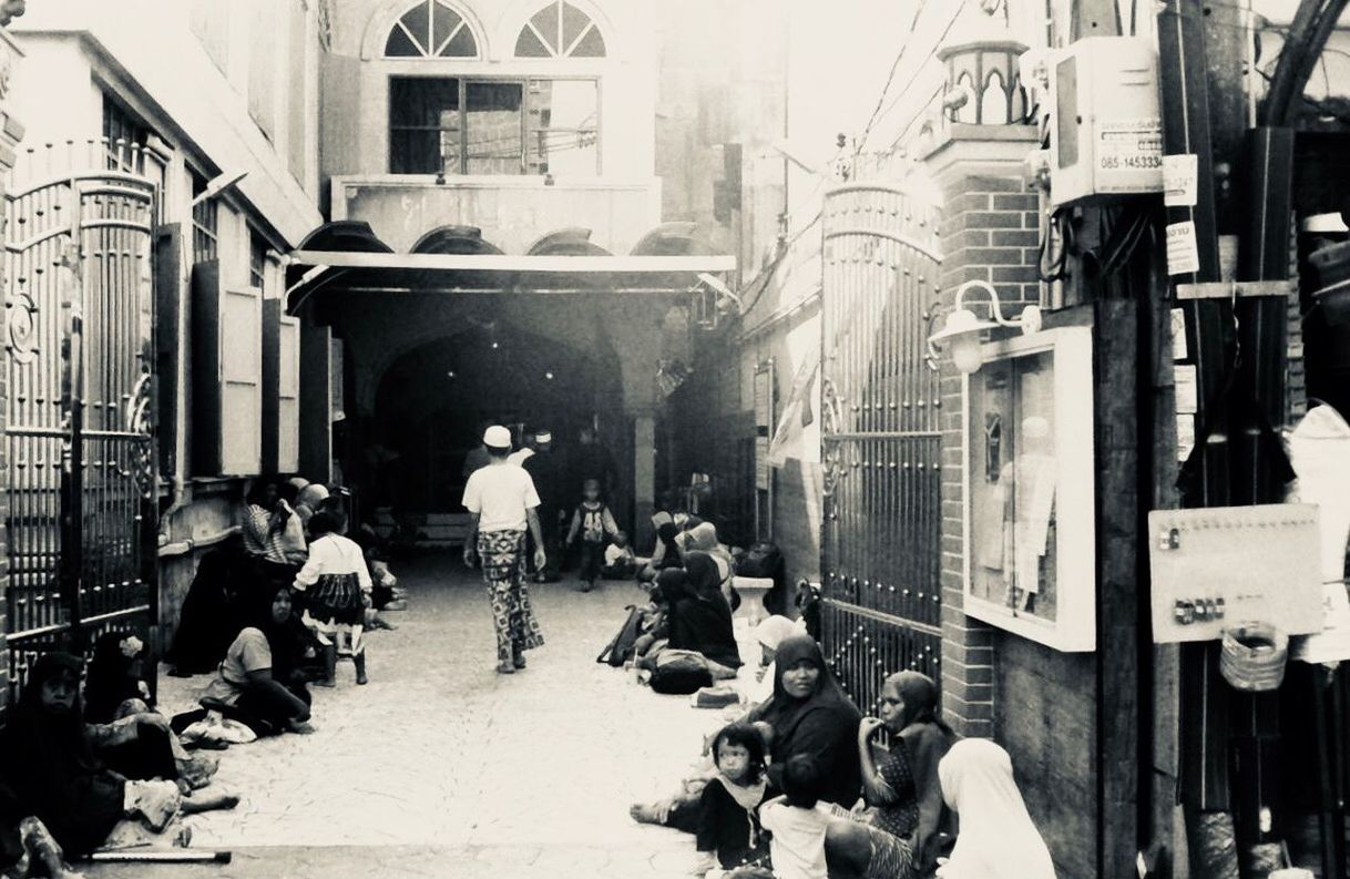 PEOPLE WALKING ON STREET AMIDST BUILDINGS