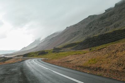 Road leading towards mountains against sky