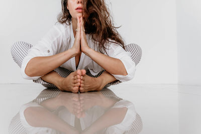 Midsection of woman sitting on bed at home