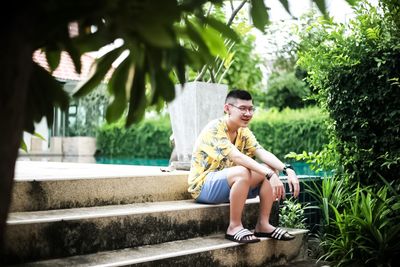 Smiling teenage boy sitting on staircase by plants