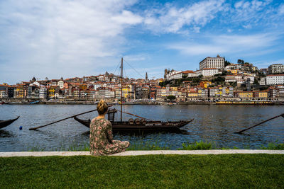 Man by river against buildings in city