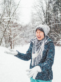 Portrait of young woman standing on snow covered field