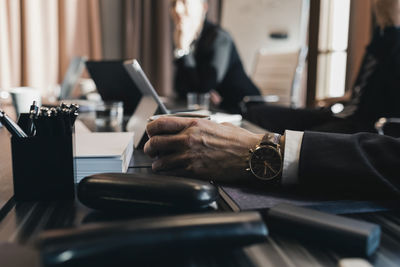 Hand of senior businessman holding coffee cup at conference table in board room during meeting