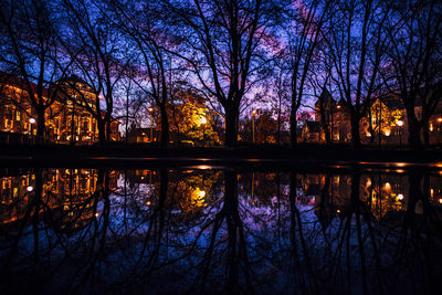 Silhouette bare trees by lake against sky during sunset