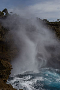 Scenic view of waterfall against sky