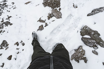 Low section of person standing on snowcapped mountain