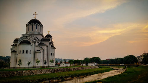 Church by building against sky during sunset