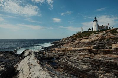 Lighthouse by sea against sky