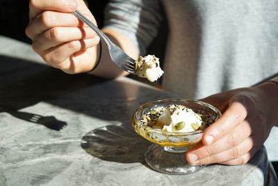 Young woman holding a scoop of yoghurt, seeds and honey sunlight..