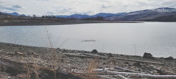 Scenic view of lake by snowcapped mountains against sky