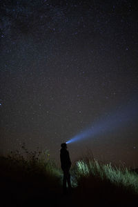 Woman with flashlight standing against star field 