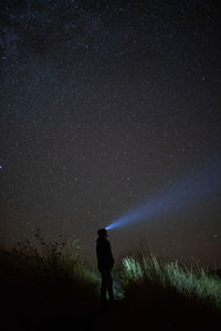 Silhouette person standing on field against sky at night