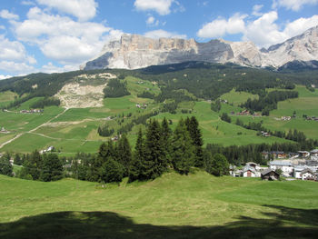 Alpine landscape with la villa village, green pastures and firs against italian dolomites at summer