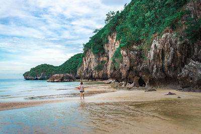 Rear view of woman standing at beach