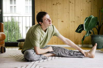 Man with eyes closed doing stretching while sitting at home