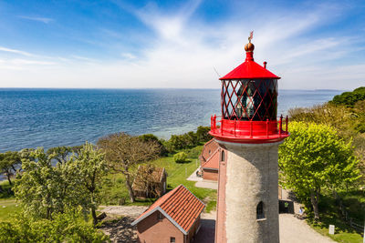 Red lighthouse by sea against sky