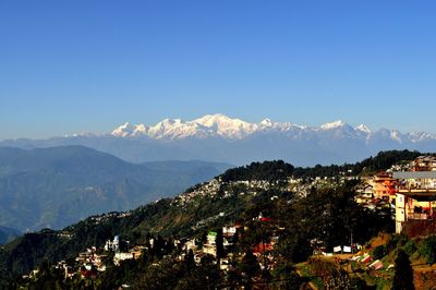 Town by mountains against clear blue sky