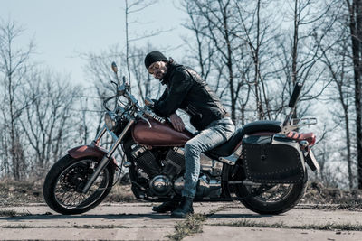 Mid adult man sitting on motorcycle in forest