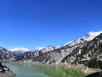 Scenic view of snowcapped mountains and lake against blue sky