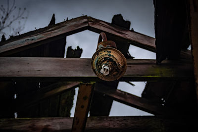 Low angle view of rusty wheel against sky