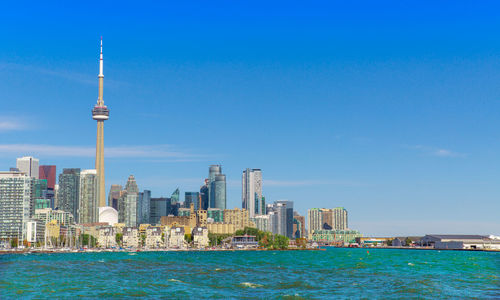 Sea and buildings against blue sky