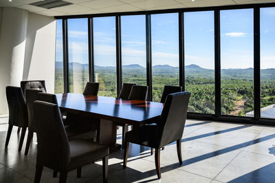 Empty chairs and table against window