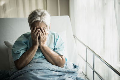 Sad senior woman sitting on bed at hospital