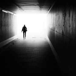 Rear view of silhouette woman walking in tunnel