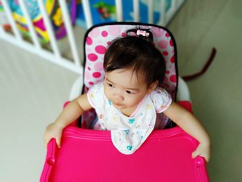 High angle view of baby girl on high chair at home